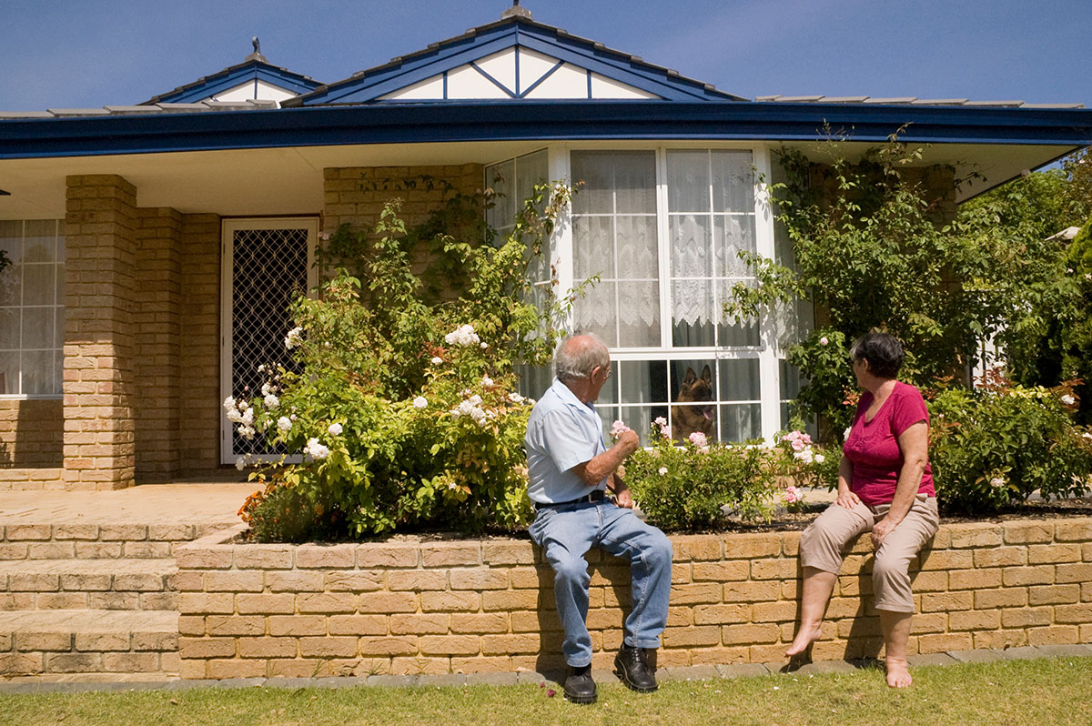 Man and Woman sitting on side of flower bed